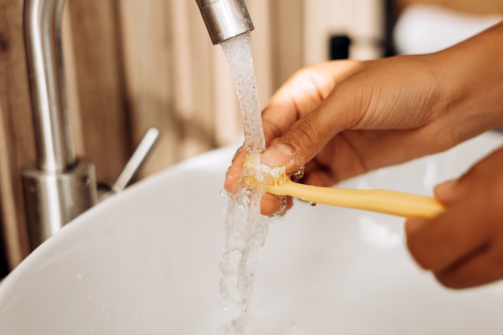 Nahaufnahme einer Hand, aus der Wasser aus einem Wasserhahn über einen Gegenstand oder die Handfläche läuft.