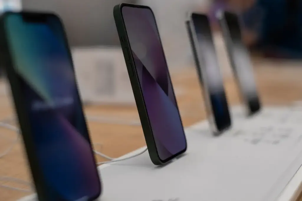 Mehrere ausgestellte Smartphones, die auf einem Tisch in einer Technikabteilung stehen.