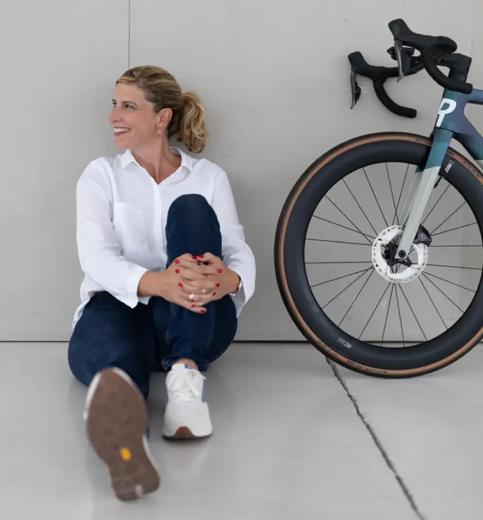 Junge Frau sitzt entspannt neben Fahrrad – Sinnbild für finanzielle Freiheit, Flexibilität und unabhängigen Lifestyle