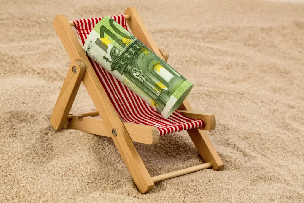 Geldscheine auf einem Liegestuhl am Strand als Symbol für finanzielle Freiheit | Financipation Club